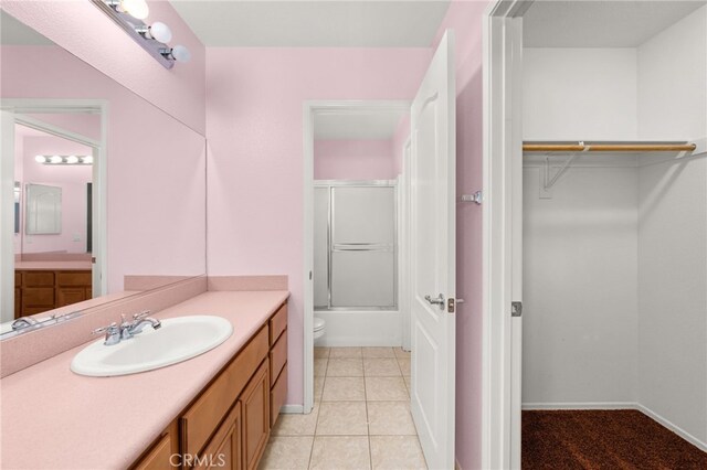 bathroom with tile patterned flooring, vanity, and bath / shower combo with glass door