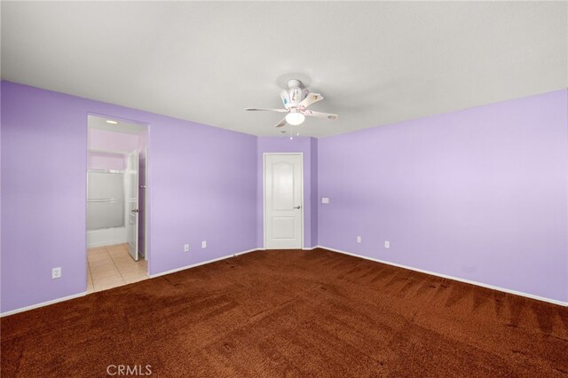 unfurnished bedroom with ensuite bathroom, a walk in closet, ceiling fan, light carpet, and a closet