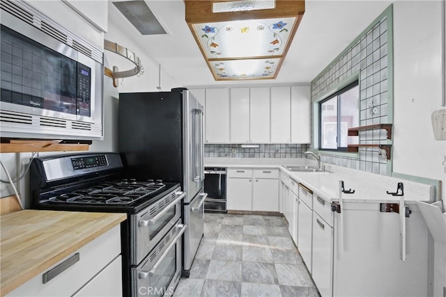 kitchen featuring backsplash, sink, stainless steel appliances, and white cabinetry