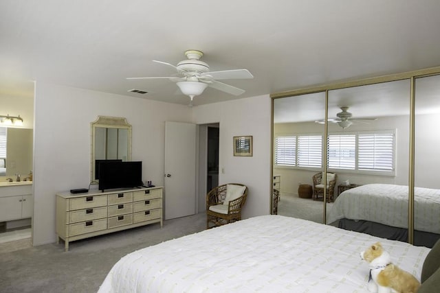 carpeted bedroom with ceiling fan, sink, connected bathroom, and a closet