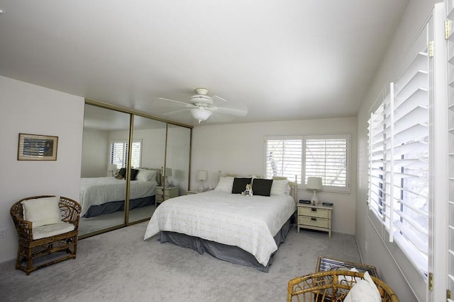 carpeted bedroom with ceiling fan, a closet, and multiple windows