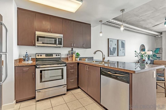 kitchen with appliances with stainless steel finishes, decorative light fixtures, sink, kitchen peninsula, and light tile patterned floors