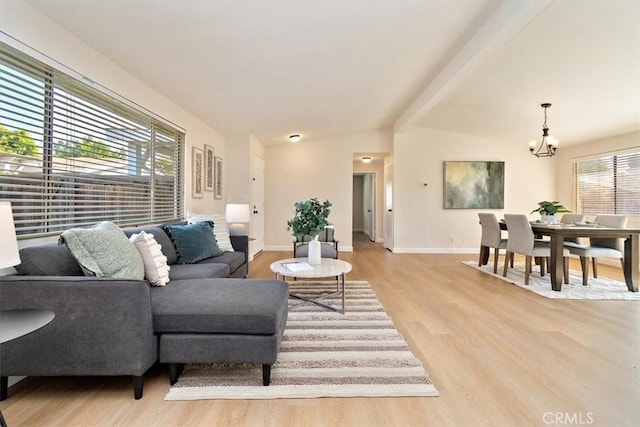 living room with beam ceiling, a notable chandelier, and light hardwood / wood-style flooring