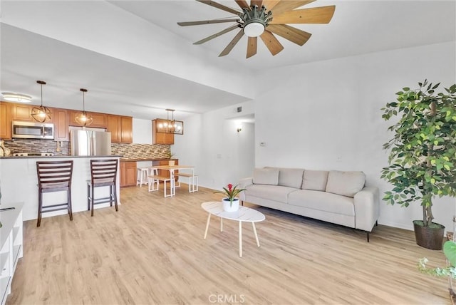 living room featuring light wood-type flooring and ceiling fan with notable chandelier