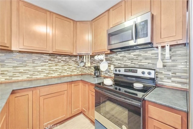 kitchen with stainless steel appliances, light brown cabinetry, and backsplash