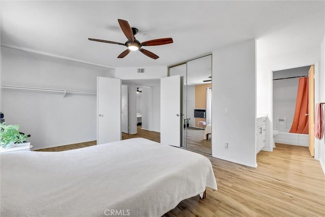 bedroom with light wood-type flooring, ceiling fan, and ensuite bathroom