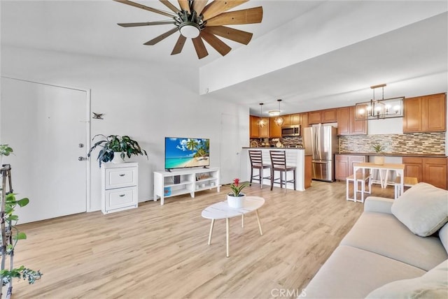 living room with light wood-type flooring and ceiling fan with notable chandelier