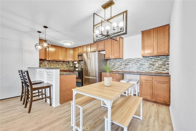 kitchen featuring an inviting chandelier, light hardwood / wood-style floors, kitchen peninsula, appliances with stainless steel finishes, and decorative light fixtures