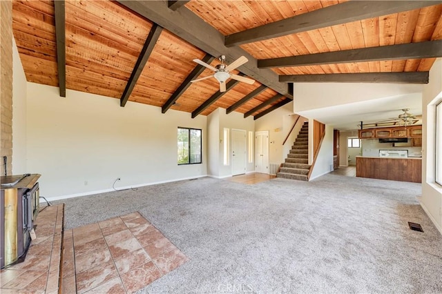 unfurnished living room with wood ceiling, light colored carpet, ceiling fan, and a wood stove