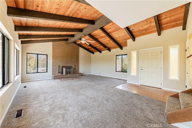 unfurnished living room with high vaulted ceiling, a fireplace, beamed ceiling, carpet flooring, and wooden ceiling