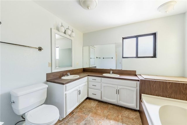 bathroom featuring vanity, a washtub, and toilet