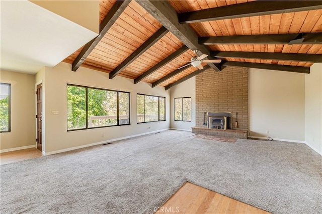 unfurnished living room with a brick fireplace, a wealth of natural light, wood ceiling, and beam ceiling