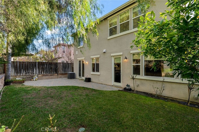 rear view of property with central air condition unit, a patio area, and a yard