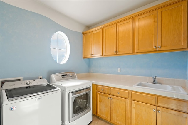 clothes washing area featuring washer and dryer, cabinets, light tile patterned floors, and sink