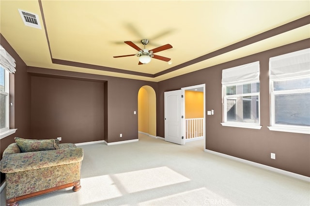 sitting room featuring ceiling fan, light colored carpet, and a tray ceiling