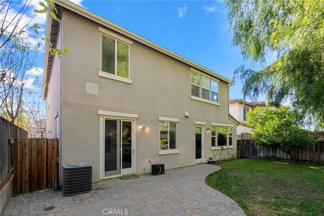 rear view of house featuring central AC unit, a yard, and a patio