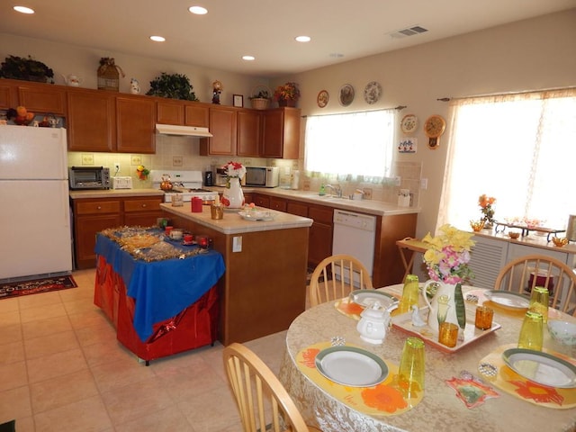 kitchen featuring tasteful backsplash, sink, white appliances, and a center island