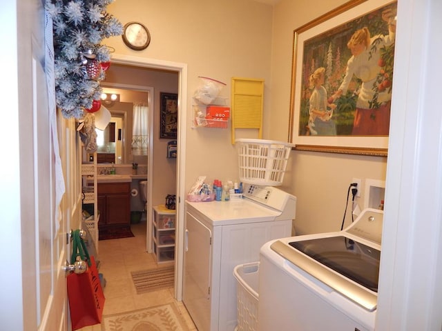 laundry area featuring light tile patterned floors, washing machine and clothes dryer, and sink