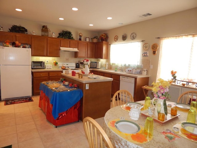 kitchen featuring light tile patterned floors, backsplash, white appliances, a kitchen island, and sink