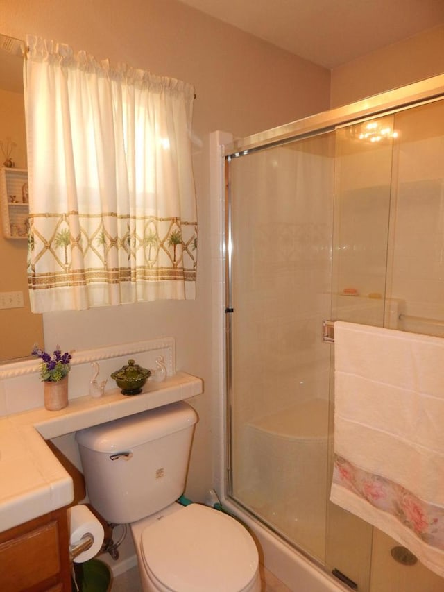 bathroom with walk in shower, vanity, and toilet