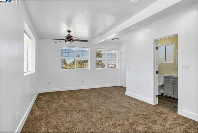 unfurnished bedroom featuring ceiling fan, connected bathroom, and dark colored carpet