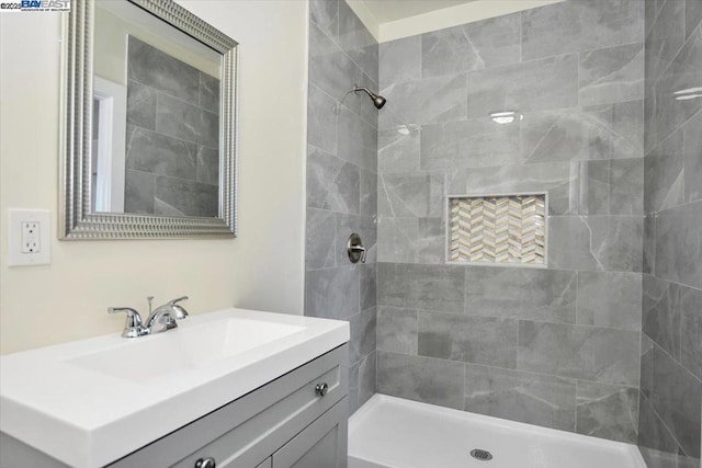 bathroom with a tile shower and vanity