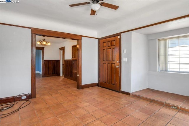 entrance foyer featuring wood walls and ceiling fan with notable chandelier