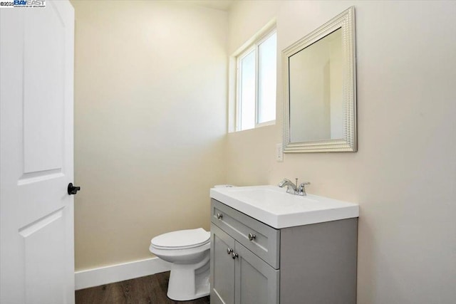 bathroom with toilet, vanity, and wood-type flooring