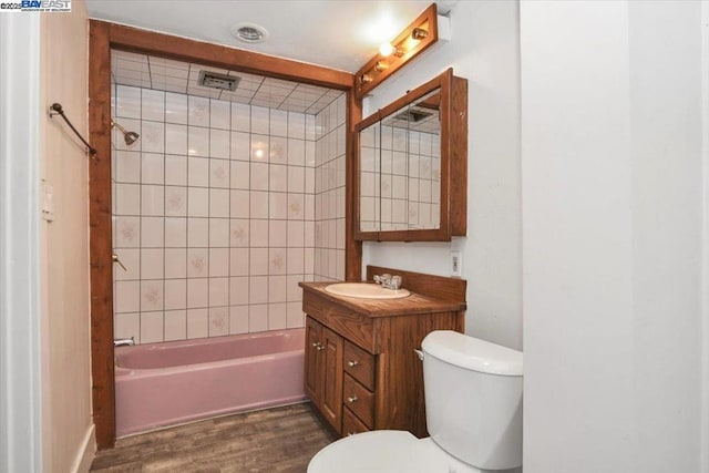 full bathroom featuring toilet, tiled shower / bath combo, hardwood / wood-style floors, and vanity