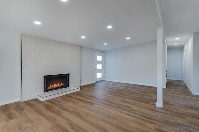 unfurnished living room with hardwood / wood-style flooring and a tiled fireplace