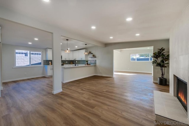 unfurnished living room featuring a tile fireplace, dark hardwood / wood-style flooring, beamed ceiling, and a healthy amount of sunlight