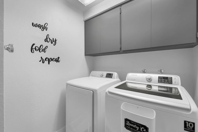 clothes washing area with washing machine and dryer and cabinets