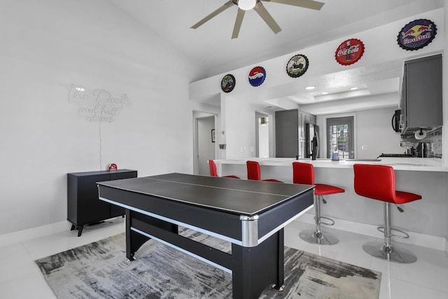 recreation room with ceiling fan, light tile patterned floors, and vaulted ceiling