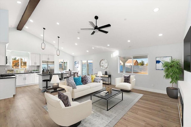 living room featuring ceiling fan, light hardwood / wood-style flooring, and vaulted ceiling with beams