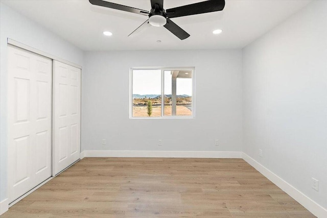 unfurnished bedroom with ceiling fan, a closet, and light wood-type flooring