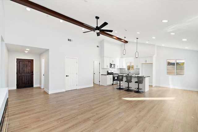 living room with beamed ceiling, sink, high vaulted ceiling, ceiling fan, and light hardwood / wood-style flooring