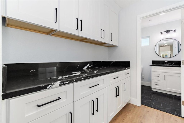 kitchen featuring white cabinets, dark stone counters, and sink