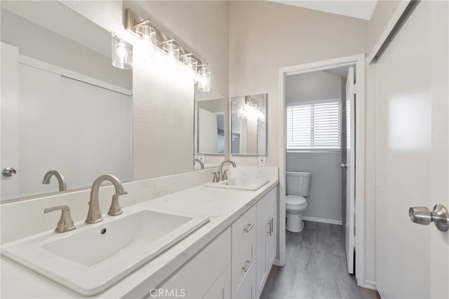 bathroom with wood-type flooring, toilet, vanity, and lofted ceiling