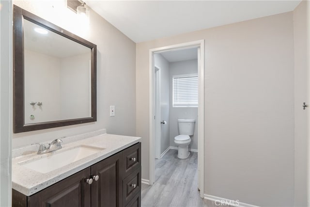 bathroom with toilet, wood-type flooring, and vanity