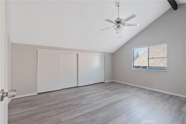 unfurnished bedroom with ceiling fan, a closet, lofted ceiling with beams, and light wood-type flooring