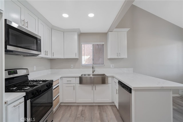 kitchen featuring white cabinets, stainless steel appliances, sink, kitchen peninsula, and light wood-type flooring