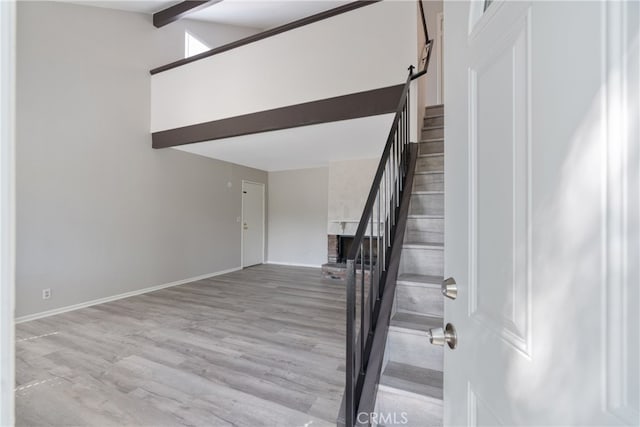 stairway featuring hardwood / wood-style floors, a fireplace, and vaulted ceiling with beams