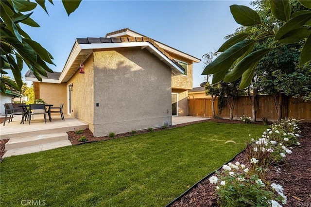 rear view of house featuring a lawn and a patio