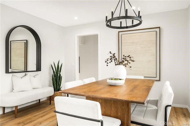 dining space with light hardwood / wood-style flooring and a chandelier