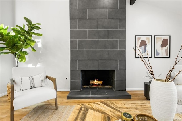 sitting room with wood-type flooring, beamed ceiling, and a fireplace