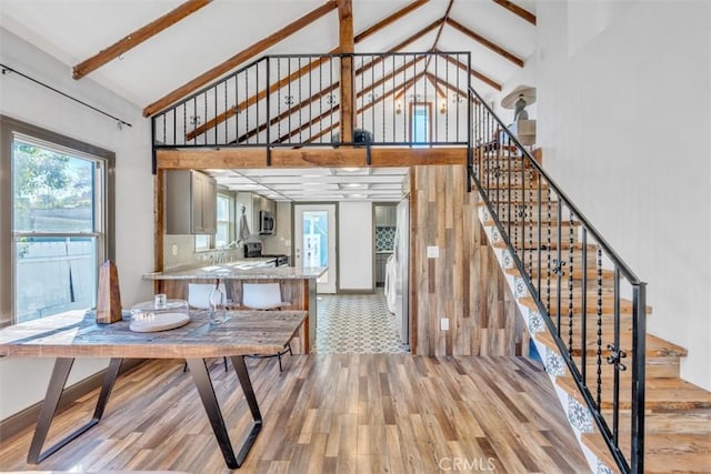 dining room with high vaulted ceiling and light wood-type flooring