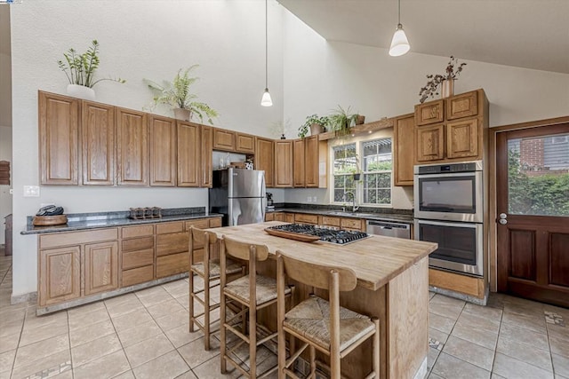 kitchen with sink, hanging light fixtures, appliances with stainless steel finishes, and a kitchen island