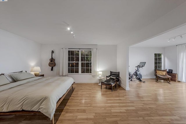 bedroom with track lighting and light hardwood / wood-style flooring