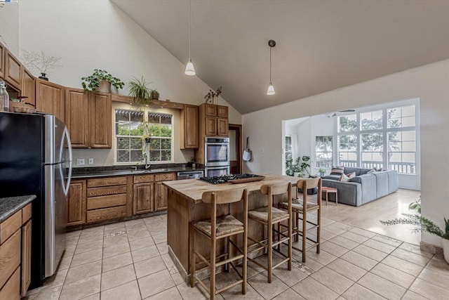 kitchen featuring light tile patterned floors, a breakfast bar area, stainless steel appliances, and high vaulted ceiling