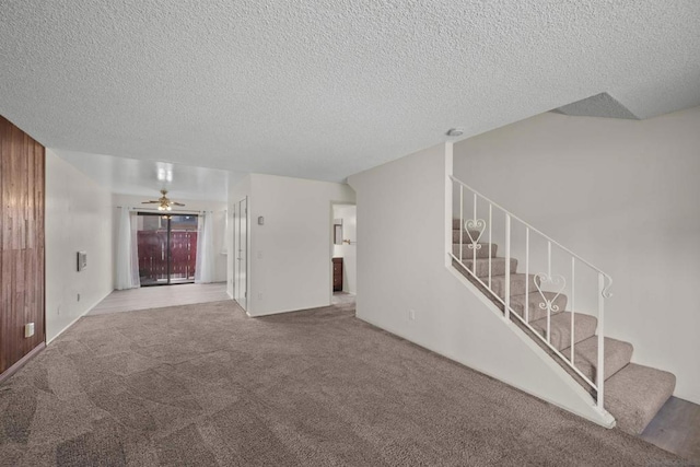 unfurnished living room with ceiling fan, a textured ceiling, and carpet flooring